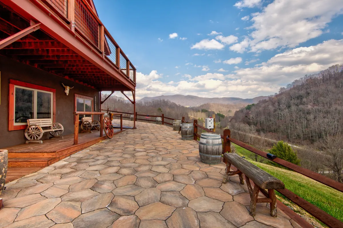 A rustic wooden deck with benches and barrels overlooks a sweeping mountain backdrop. The tranquil scene highlights the connection to nature, with opportunities for enjoying the view, sipping coffee, or stargazing after a day of productivity.